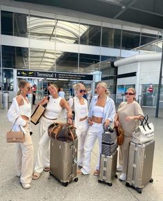 four women are standing with their luggage at the airport