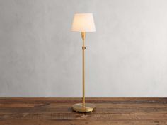 a floor lamp with a white shade on the top and a wooden table below it