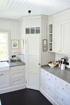 a kitchen with white cabinets and gray counter tops