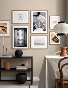 a dining room with pictures on the wall and a table in front of it next to a lamp