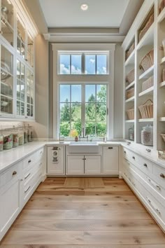 a kitchen with lots of white cabinets and drawers on the wall, along with an open window