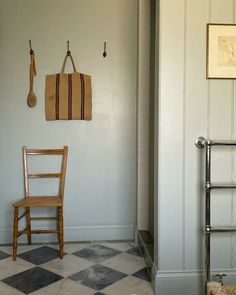 a wooden chair sitting in front of a white wall next to a towel rack and radiator