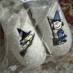 two white slippers with cartoon characters on them sitting in plastic bags next to a rug