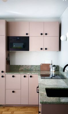 a kitchen with pink cabinets and marble counter tops