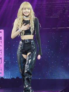 a woman in black pants and crop top on stage with her arms around her chest