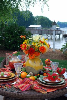 an outdoor table set up with plates and flowers in vases on top of it