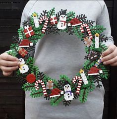 a person holding a beaded christmas wreath