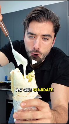 a man eating an ice cream sandwich with a spoon in his hand while looking at the camera