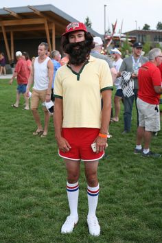 a man in red shorts and a yellow shirt is standing on the grass with other people behind him