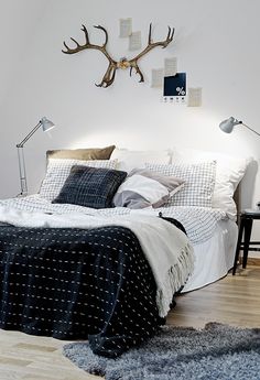 a bedroom with antlers mounted to the wall above the bed and pillows on the floor