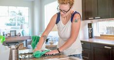 a woman cleaning the kitchen counter top with a green glove and cloth in her hand