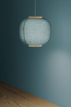 a wooden table with a lamp hanging from it's side and a blue wall in the background