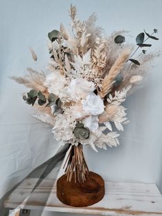 an arrangement of dried flowers and foliage in a vase