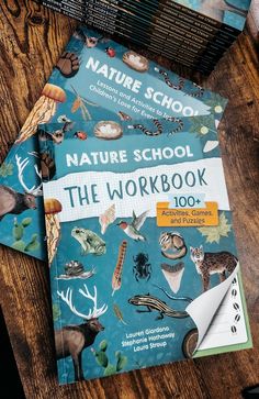 the nature school workbook is on top of a wooden table with other books and pens