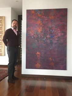 a man standing in front of a painting on the wall next to a wooden floor