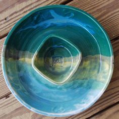 a blue and green bowl sitting on top of a wooden table