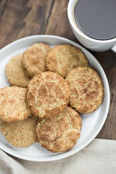 a white plate topped with cookies next to a cup of coffee