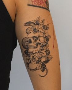 a woman's arm with a skull and flowers tattoo on the left side of her body