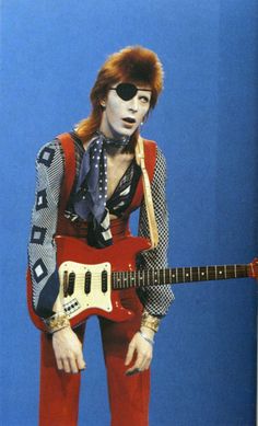 an image of a man holding a guitar in front of a red and yellow background