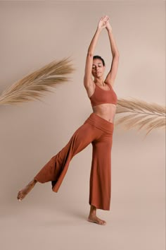 a woman standing in the middle of a dance pose with her arms up and legs spread out