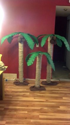 three palm trees made out of toilet paper in a room with hard wood flooring