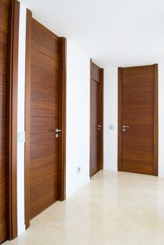 three wooden doors in an empty room with white walls and flooring on either side