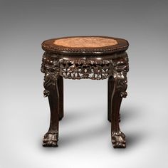 an ornately carved wooden table with carvings on the top and bottom, sitting against a gray background