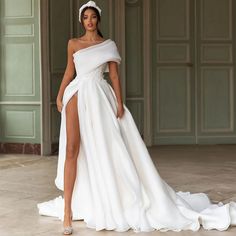 a woman in a white wedding dress with a slit down the side and one leg