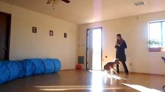 a woman standing in an empty room with a dog on the floor next to her