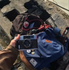 a person holding a camera in front of a blue bag on the ground next to a fire hydrant