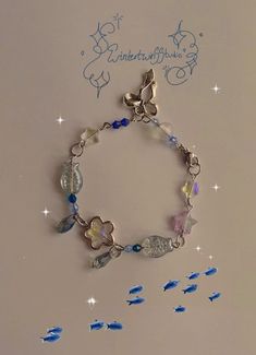 a bracelet with blue and white beads, butterflies and stars on the bottom is attached to a silver chain