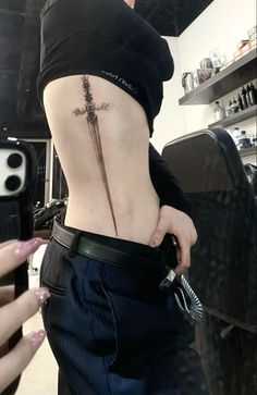 a woman with a cross tattoo on her lower back is holding a knife in her right hand