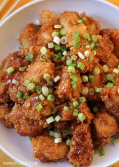 a white plate topped with meat covered in sauce and green onions