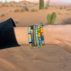 a person's arm with three bracelets on it in the middle of desert