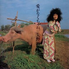 a woman standing next to a cow in a field