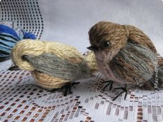 two small birds sitting on top of a white cloth covered table next to each other