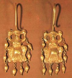 two gold earrings with small figures on them