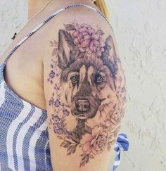 a woman with a tattoo on her shoulder has a dog and flowers in her hair