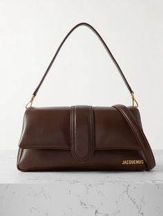 Whether they were watching in person or on Instagram, Jacquemus fans were eagerly awaiting the release of new bags in the 'Le Raphia' collection. This mini 'Le Bambimou' style has been made in Italy from buttery leather that's padded for a squishy shape and feel. It's detailed with signature gold hardware. Jacquemus Shoulder Bag, Designer Brown Baguette Bag For Evening, Luxury Brown Soft Leather Baguette Bag, Brown Baguette Evening Bag, Brown Calf Leather Bag With Magnetic Closure, Luxury Brown Leather Baguette Bag, Brown Baguette Bag For Evening, Jacquemus Logo, Designer Things