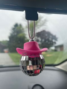 a pink hat hanging from the side of a car window with mirror balls attached to it