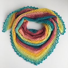 a multicolored crocheted scarf on a white surface