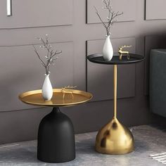 two black and gold tables with vases on them