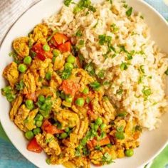 a white plate topped with rice and vegetables next to a bowl filled with chicken curry