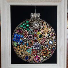 an ornate christmas ornament is displayed in a white frame on a wooden table