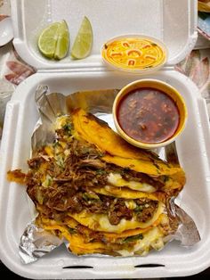 a take out container with some tacos and sauce on the side, along with condiments