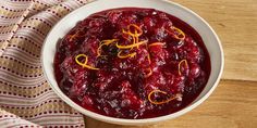 a white bowl filled with cranberry sauce on top of a wooden table next to a napkin