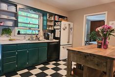 a kitchen with black and white checkered flooring, green cabinets and wooden table