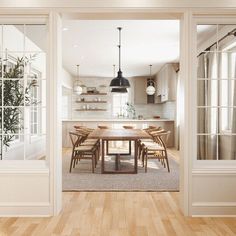 an open door leading to a kitchen and dining room with wood floors, white walls and cabinets