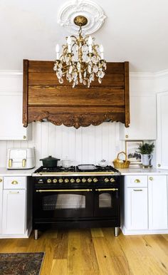 a black stove top oven sitting inside of a kitchen next to white cabinets and a chandelier