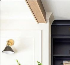 a black book shelf with books and plants on it in front of a white wall